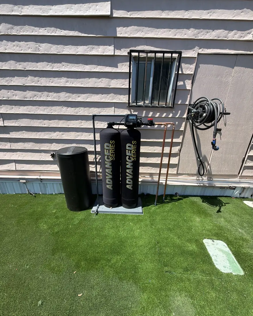 Twin-tank water treatment system with jacketed tanks and a brine tank installed outside a home