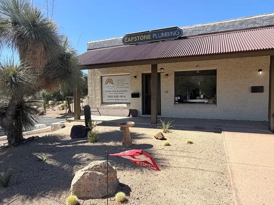 Capstone Plumbing's storefront on E Cave Creek Rd in Cave Creek, Arizona, with desert landscaping and an OPEN flag out front