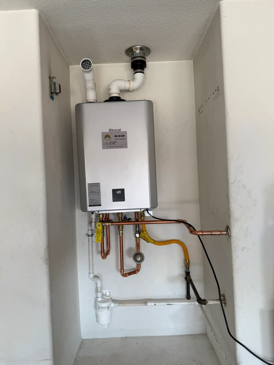 Rinnai tankless water heater installed by Capstone Plumbing in a utility alcove, with copper supply lines, isolation service valves, a flexible gas connector, condensate drain and PVC intake and exhaust venting, Cave Creek AZ